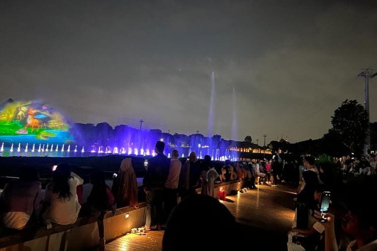 Pengunjung Taman Mini Indonesia Indah (TMII) nampak memadati wahana air mancur menari atau Dancing Fountain Tirta Cerita pada libur Lebaran kedua, Kamis (11/4/2024). 